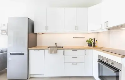 a kitchen with white cabinets and a stainless steel refrigerator at Modern apartment ONLY 5 minutes from City centre in Bergen