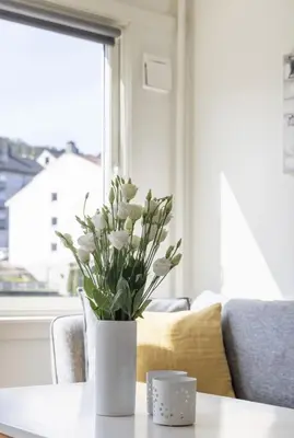 a white vase with white flowers on a table at Modern apartment ONLY 5 minutes from City centre in Bergen
