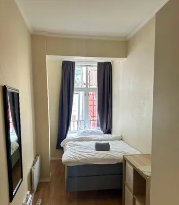 a bed in a room with a window at Koselig bygårdsleilighet i Bergen sentrum in Bergen
