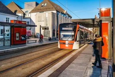 a train pulling into a train station with a person standing next to it at Newly Renovated Rom Bergen Fana in Bergen