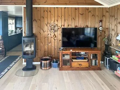 a living room with a television and a wood wall at Modern Cabin With Views In Lygna in Jaren