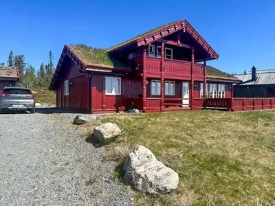 a red house with a car parked in front of it at Modern Cabin With Views In Lygna in Jaren