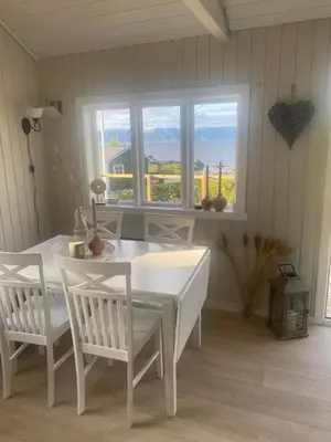 a white table and chairs in a room with a window at Koselig hytte nær sandstrand in Langenes
