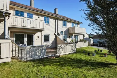 a large white house with a porch and a yard at Furnished apartment near Aker Solutions in Stord
