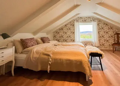 a bedroom with a bed and a window at Hyggelig Gård Nær Bergen Med Spabad in Hjelmås