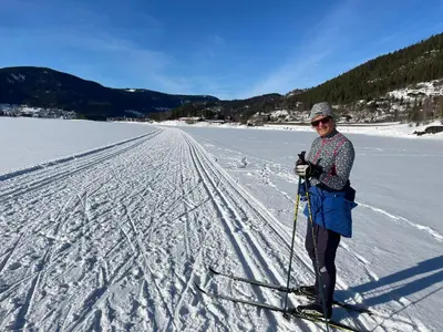 a woman is standing on skis in the snow at Koselig, lita hytte på Aurdalsåsen ved Danebu in Aurdal