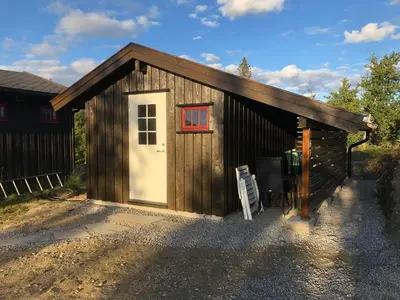 a small wooden shed with a white door at Koselig, lita hytte på Aurdalsåsen ved Danebu in Aurdal
