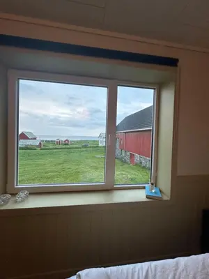 a window with a view of a field and a red barn at Location, location, location in Ervik