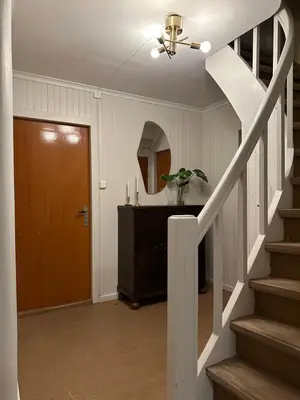 a hallway with a stairway with a door and a stair at Location, location, location in Ervik