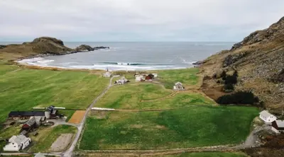 an aerial view of a house on a hill next to the ocean at Location, location, location in Ervik