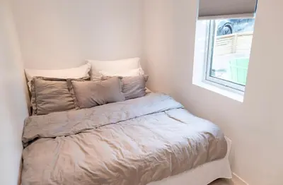 a bed in a corner of a room with a window at Lille Luxury moderne feriehus med stor uteplass, utekjøkken og pergola in Bergen