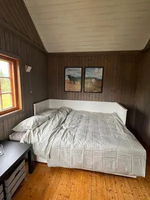a bed in a bedroom with two pictures on the wall at Koselig hytte på hugastølen in Vang I Valdres