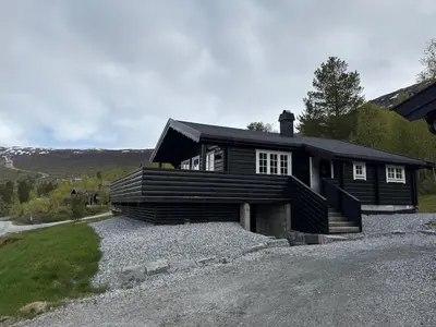 a large wooden house on a gravel driveway at No 105 Kongelberget in Bjorli