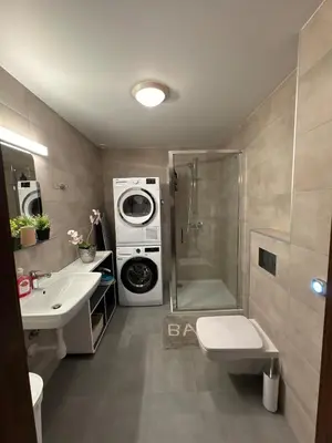a bathroom with a shower sink and a washing machine at Cozy apartment in Tennfjord in Tennfjord