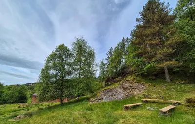 two benches sitting on a grassy hill with trees at 7 Bedroom Amazing Home In Nedre Vats in Stokka