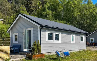 a small house with two blue chairs in front of it at 2 Bedroom Stunning Home In Lavik in Lavik