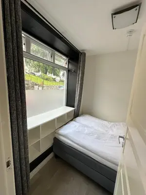 a small bedroom with a bed and a window at Cozy little apartment in Ålesund in Ålesund