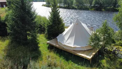 a white tent sitting on a dock next to a lake at River Glamping - Jordet, Trysil in Trysil