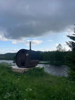a round house sitting on the side of a body of water at River Glamping - Jordet, Trysil in Trysil