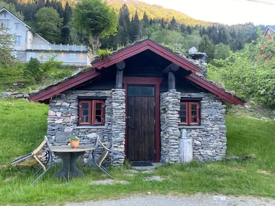 a small stone cabin with a table in front of it at Cabin in Oppstryn in Stryn