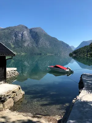 a boat on a lake with mountains in the background at Cabin in Oppstryn in Stryn