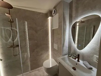 a bathroom with a shower and a sink and a mirror at New Modern Apartment Near Tram Fantoft in Bergen