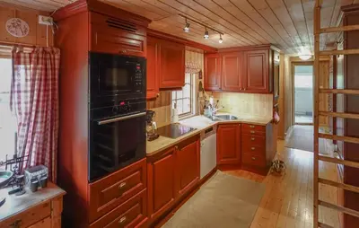 a kitchen with red cabinets and a black stove top oven at Awesome Home In Uvdal With Sauna in Uvdal