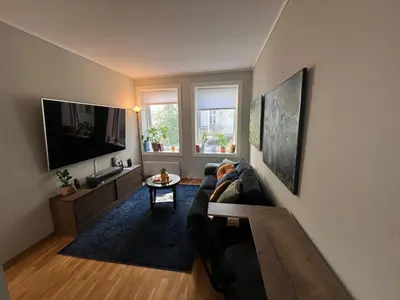 a living room with a couch and a flat screen tv at Cozy Gem in the Heart Of Bergen in Bergen