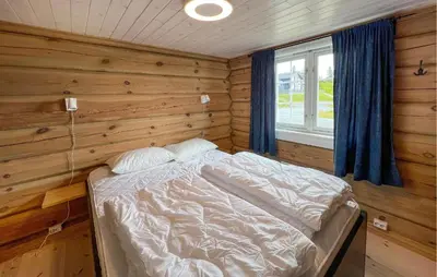 a bedroom with a bed in a wooden wall at Cozy Home In Sjusjøen With Wifi in Sjusjøen