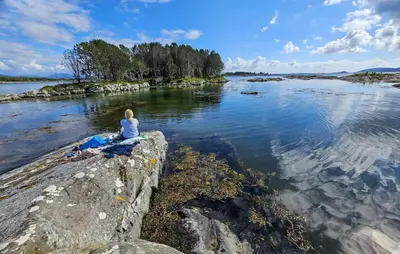 a woman sitting on a rock in the water at Cozy Home In Florø With Wifi in Florø