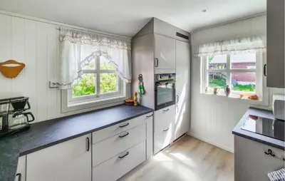a kitchen with white cabinets and two windows at Nice Home In Eikelandsosen With Wifi in Eikelandsosen