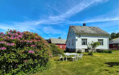 a white house with a table and chairs in the yard at Nice Home In Eikelandsosen With Wifi in Eikelandsosen