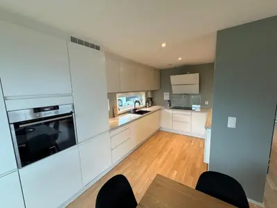 a kitchen with white cabinets and a table and chairs at Luksuriøs enebolig, nær Ålesund in Ytterland