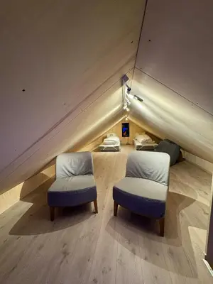 a room with two chairs and a bed in a attic at Modern Cabin Near Auersvatn And Ski Trails in Hovden