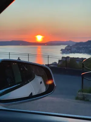 a rear view mirror of a car with the sunset in the background at Floien City Apartment -Free parking in Bergen