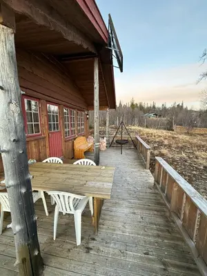 a wooden deck with a table and chairs on a cabin at Spacious mountain cabin in Valdres with 3 bedrooms in Vevle
