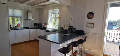 a kitchen with a counter and stools in it at Waterfront Villa Boat Included, Near Bergen in Lindås