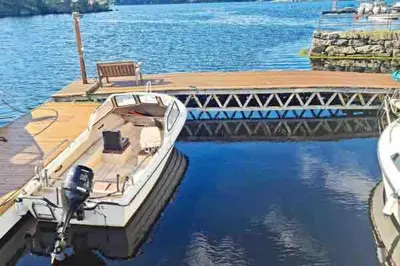 a boat docked at a dock with a bench at Waterfront Villa Boat Included, Near Bergen in Lindås