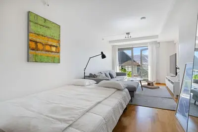 a white bedroom with a large bed and a couch at Central Bergen apt w Balcony in Bergen