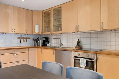 a kitchen with wooden cabinets and a table and chairs at Central Bergen apt w Balcony in Bergen