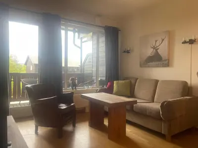 a living room with a couch and a table and a window at Sentral, Hc-Friendly Apartment in Beitostøl