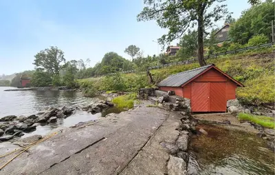 a small red building next to a body of water at Nice Home In Aksdal With House Sea View in Aksdal