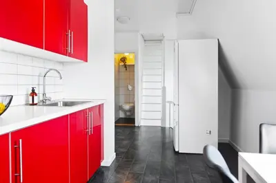 a kitchen with red cabinets and a white refrigerator at Townhouse with free parking in the city centre - 4 bedrooms in Ålesund