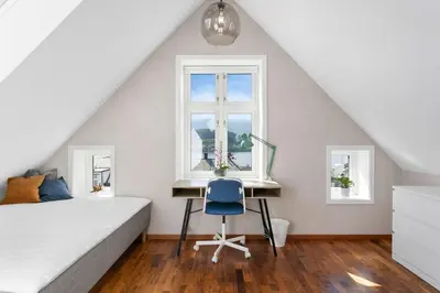 a bedroom with a bed and a desk and a window at Large apartment with 5 bedrooms, 2 bathrooms and roof terrace in Ålesund