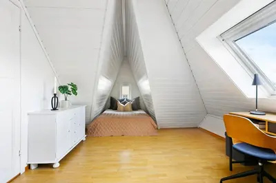 an attic bedroom with a bed and a desk at City apartment with 4 bedrooms & private terrace in Ålesund