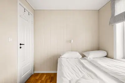 a white bedroom with two beds and a door at Bergen Charm - Right in the City Center! in Bergen