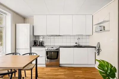 a kitchen with white cabinets and a wooden table at Bergen Charm - Right in the City Center! in Bergen