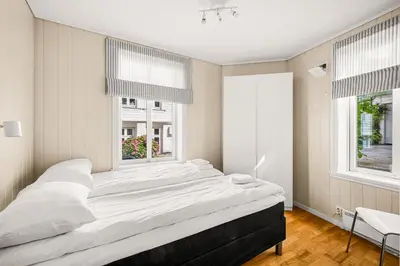 a large bed in a bedroom with two windows at Bergen Charm - Right in the City Center! in Bergen