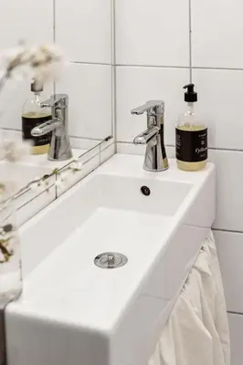 a bathroom sink with two faucets and a mirror at Bergen Charm - Right in the City Center! in Bergen