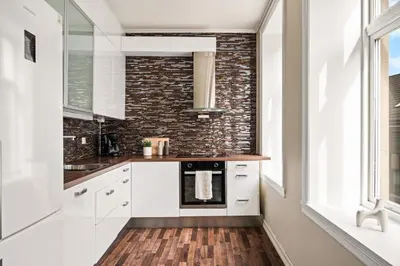 a kitchen with white cabinets and a brick wall at BB Apartments I 300m to Bryggen & Train Station in Bergen